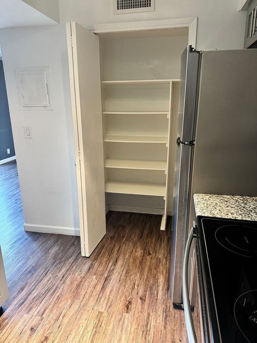 Modern kitchen space featuring sleek stainless steel appliances, elegant wood flooring, and a convenient built-in pantry.