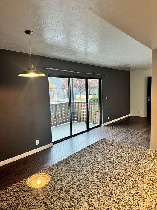 Modern open-plan living area featuring elegant wood flooring, ambient lighting, and large sliding doors leading to a private balcony.
