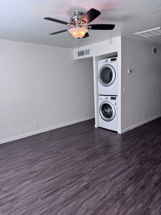 Modern apartment with sleek wood flooring, integrated washer and dryer, and stylish ceiling fan for comfort and convenience.