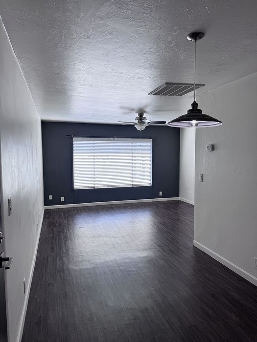 Sleek and modern living space with elegant dark hardwood floors, contemporary lighting, and a large window providing ample natural light.