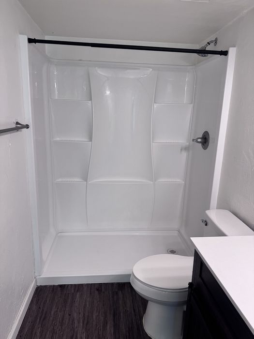 Sleek modern bathroom with a pristine white shower enclosure, elegant dark flooring, and contemporary fixtures.