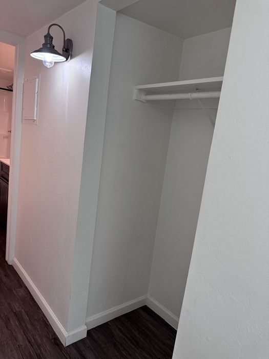 Bright, modern apartment closet with elegant lighting and sleek dark flooring.