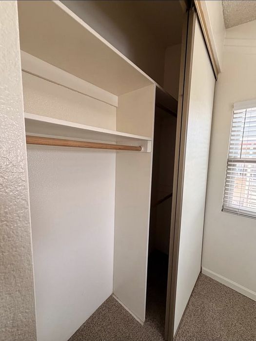 Spacious and well-lit closet with sliding doors and built-in shelving, perfect for organized storage.