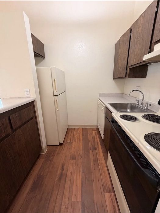 Cozy kitchen with sleek wooden cabinets, modern appliances, and elegant hardwood floors.