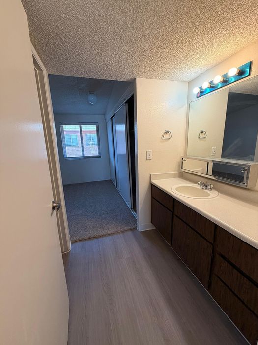Elegant apartment vanity area with bright lighting, modern sink, and spacious closet in the background.