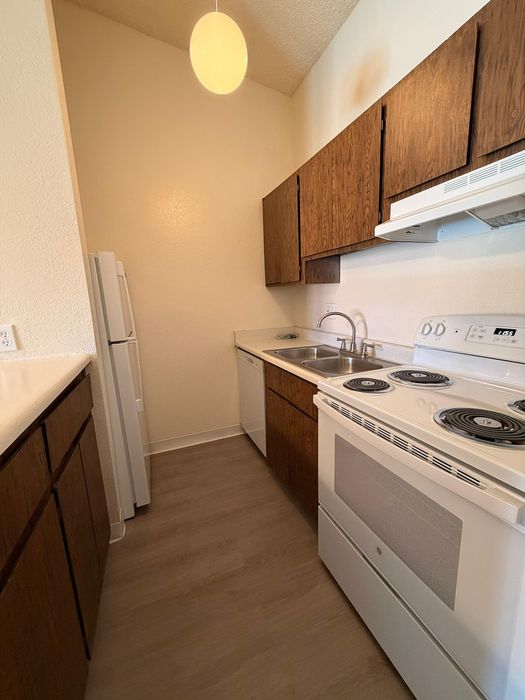 Charming kitchen with cozy lighting, light wood flooring, and sleek modern appliances.