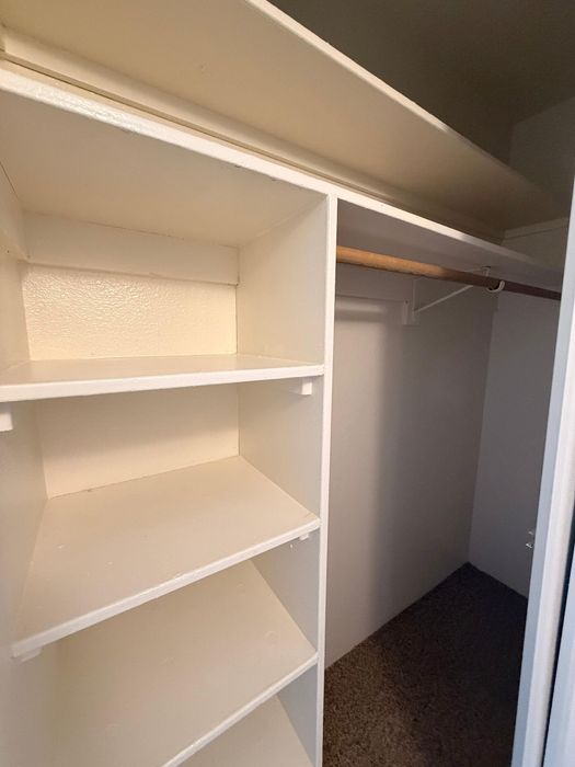Spacious walk-in closet with ample shelving and a sturdy hanging rod, perfect for organizing your wardrobe.