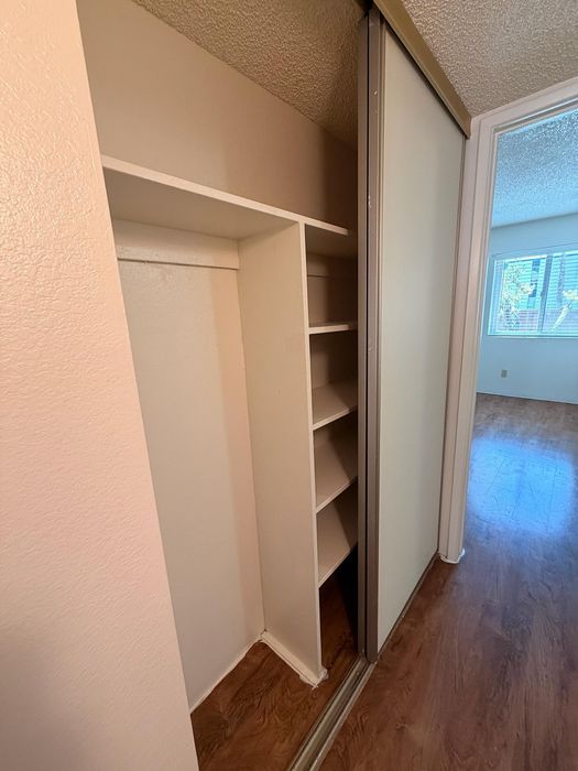 Spacious built-in closet with sliding doors and ample shelving, perfect for maximizing storage in a modern apartment.