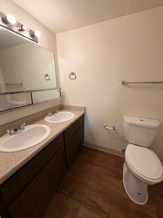 Modern bathroom with dual sinks, elegant lighting, and sleek wooden flooring, offering a stylish and functional space.