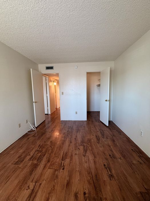 Inviting bedroom with modern wood flooring and ample closet space, perfect for a cozy and stylish living.