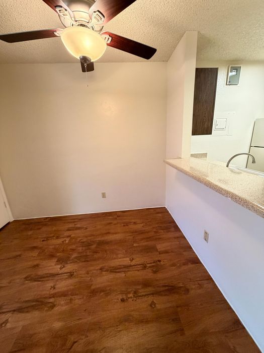Inviting dining area with elegant wood flooring, modern ceiling fan, and a sleek breakfast bar, offering a cozy space for meals and relaxation.