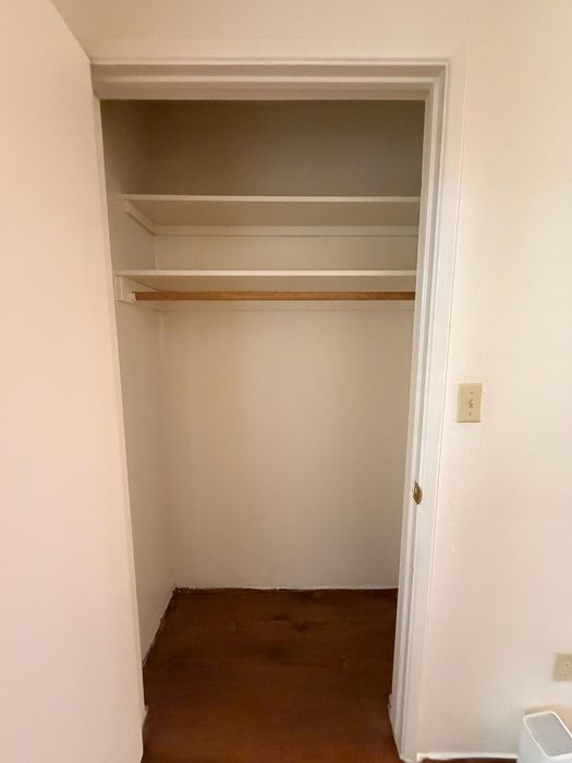 Spacious closet with wooden flooring and built-in shelves, perfect for organized storage.