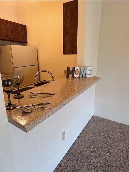 Chic kitchen nook with granite countertop, contemporary cabinets, and 'HOME' decor creates a welcoming atmosphere.