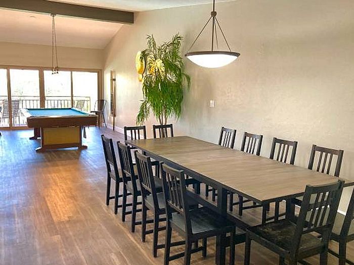 Spacious dining area with a large table, modern lighting, and a pool table with natural light.