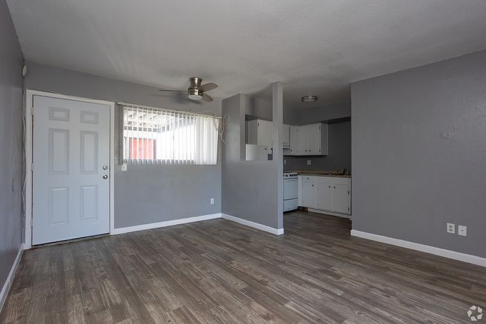 Inviting open-concept apartment with sleek gray walls, warm wood flooring, and a cozy kitchen with white cabinetry.