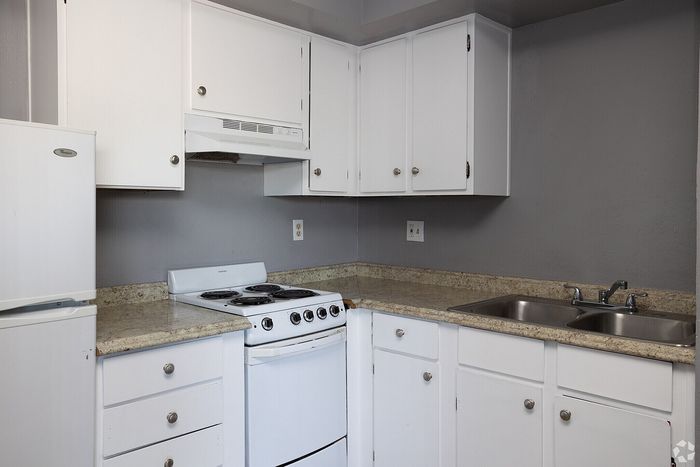 Contemporary kitchen featuring sleek white cabinets, granite countertops, and modern appliances in a stylish apartment.