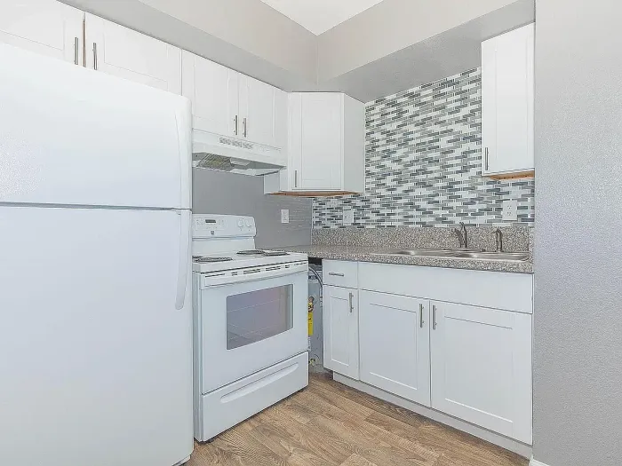 Modern AZ Commons kitchen featuring sleek white cabinets, granite countertops, and modern appliances in a stylish apartment.