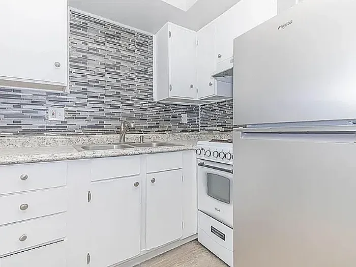 Modern AZ Commons kitchen featuring sleek white cabinets, granite countertops, and modern appliances in a stylish apartment.
