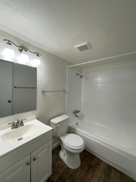 Chic apartment bathroom featuring modern lighting, elegant vanity, and sleek wood flooring.