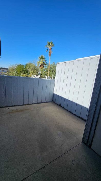 Charming balcony view featuring a sunny and private outdoor space with palm trees and clear blue skies.
