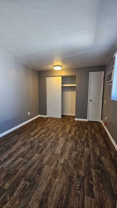 Cozy bedroom showcasing modern LED lighting, elegant hardwood floors, and a spacious closet in a stylish apartment.