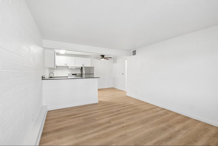 Open-plan apartment with white kitchen, stainless steel appliances and wood flooring at Miramonte on 3rd in Tucson, AZ