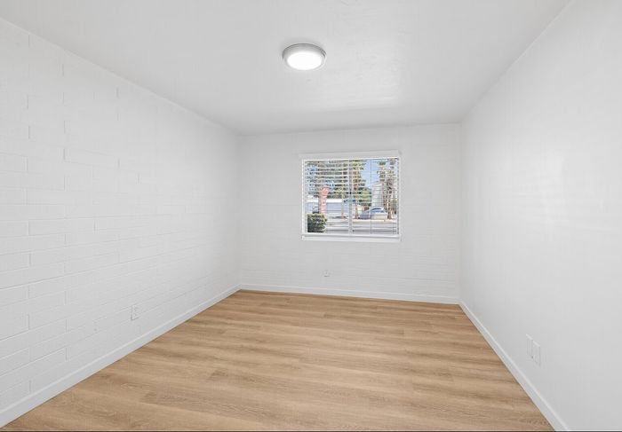 Bright bedroom with wood flooring, white walls and a large window at Miramonte on 3rd in Tucson, AZ