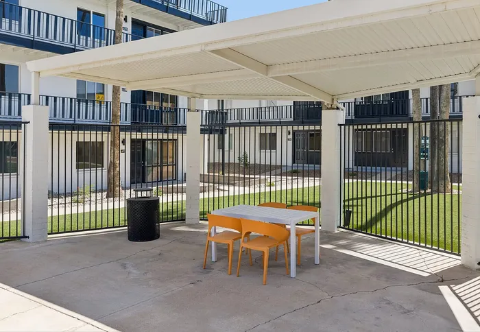 Charming outdoor area with a modern pergola, vibrant seating, and lush green surroundings, perfect for relaxation and gatherings.