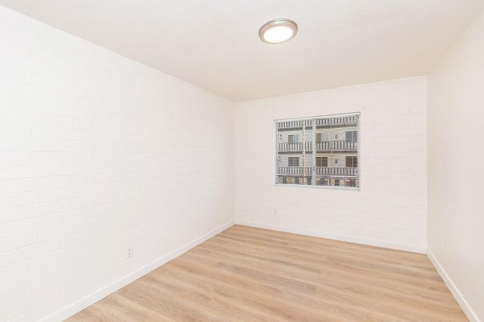 Bright and airy room with sleek wood flooring and a modern light fixture, offering a serene and inviting space.