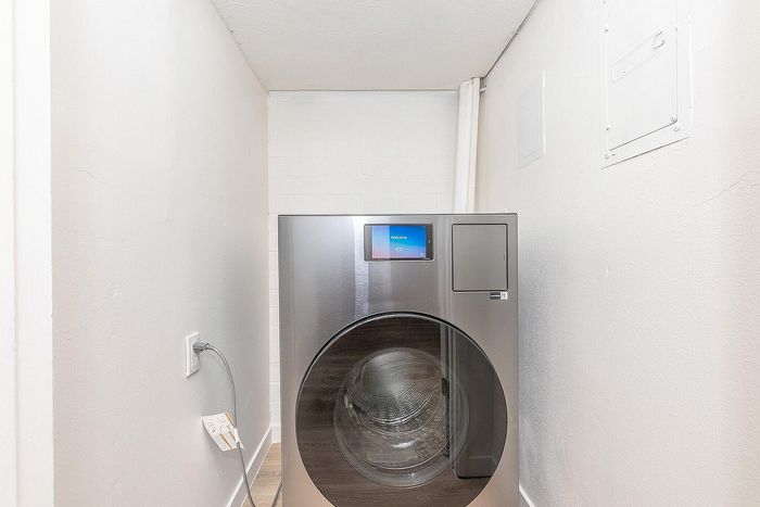 Sleek laundry area featuring a modern, high-efficiency washing machine in a compact space, ideal for urban living.