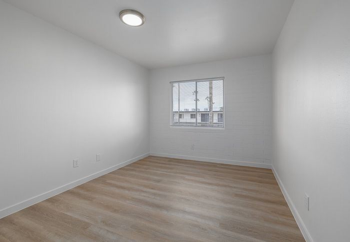 Bright and airy bedroom with large window, sleek modern lighting, and elegant wood flooring, perfect for customizing your dream space.