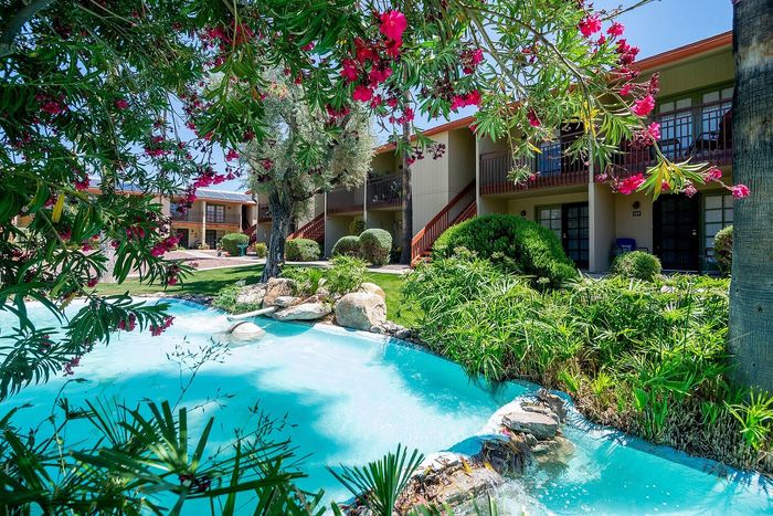 Charming apartment complex surrounded by lush greenery and a sparkling blue pond, creating a serene and inviting outdoor oasis.