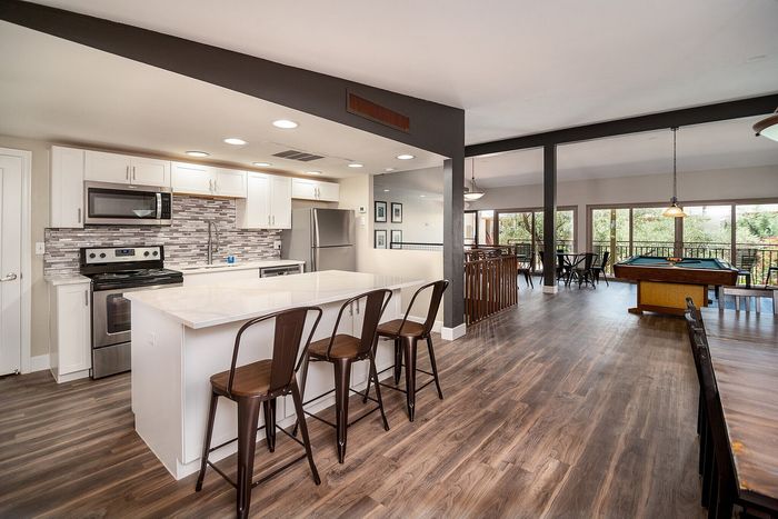 Stylish open-concept apartment featuring a modern kitchen with stainless steel appliances, elegant dining area, and spacious living room with large windows.