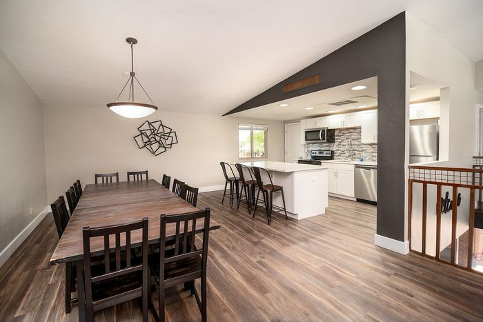 Modern open-concept dining and kitchen area with elegant hardwood floors, sleek island seating, and stylish lighting.