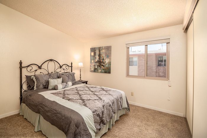 Cozy bedroom with elegant iron bed frame, plush bedding, warm lighting, and modern art on the wall, offering a welcoming and tranquil retreat.