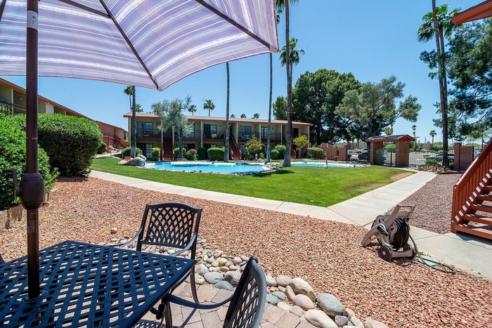 Charming poolside view with lush green lawns and inviting outdoor seating under a large patio umbrella.