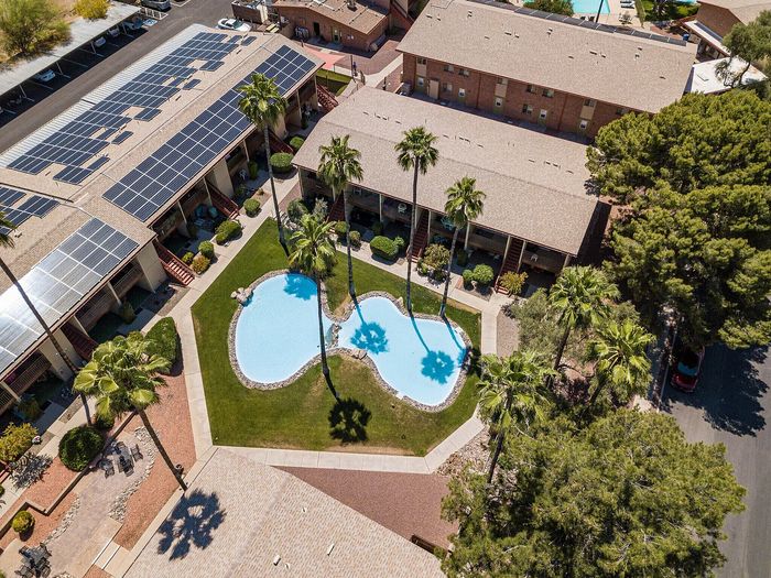 Charming apartment complex with eco-friendly solar panels, lush gardens, and a resort-style pool, perfect for relaxation and enjoyment.