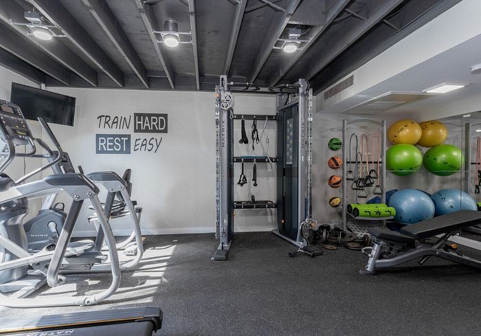 Bright, modern gym with state-of-the-art fitness equipment, colorful exercise balls, and motivational wall art.