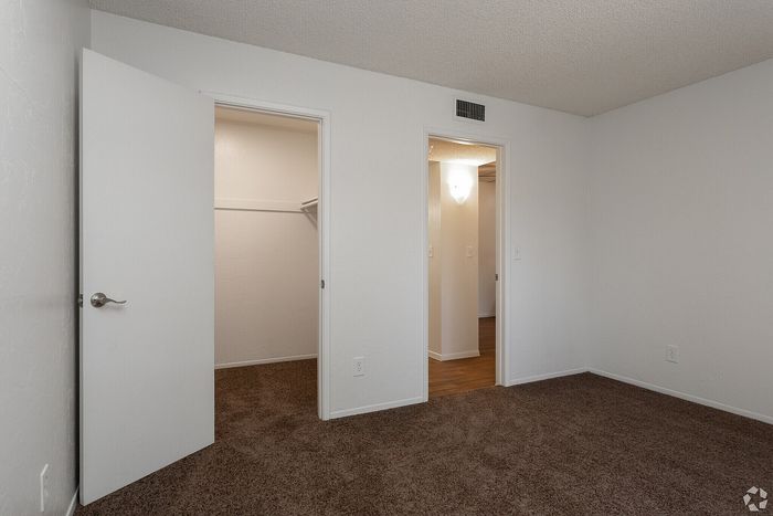 Inviting bedroom with plush carpet, featuring a walk-in closet and soft lighting, ideal for a cozy living space.