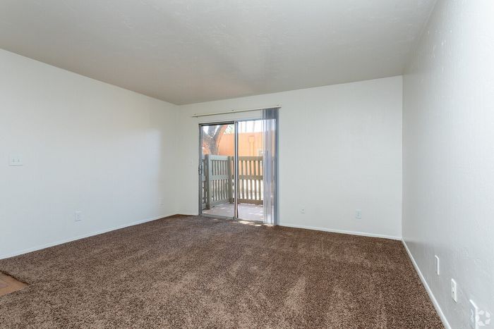 Bright and spacious living area with plush carpet and sliding doors leading to a private patio.