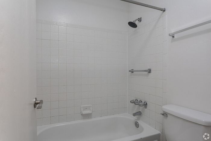 Pristine bathroom showcasing a classic white-tiled shower and bathtub with modern fixtures and a convenient towel rack.