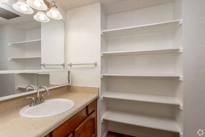 Bright bathroom with elegant over-sink lighting, ample shelving, and a sleek vanity featuring a contemporary faucet.