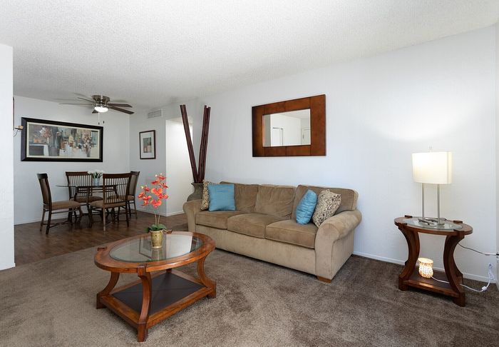Inviting living room featuring a cozy sofa, elegant wooden furniture, and a charming dining area, perfect for relaxation and entertaining.
