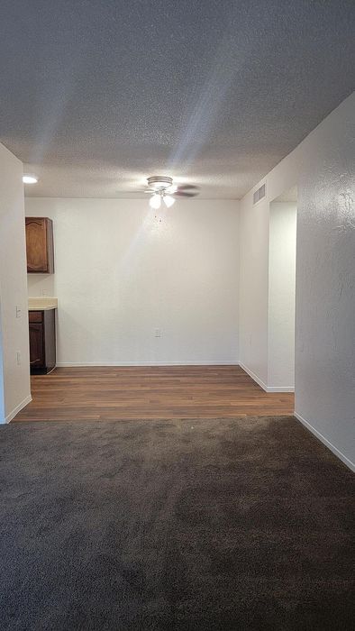 Inviting open-concept space featuring elegant wood flooring, plush carpeting, and a cozy corner perfect for dining.