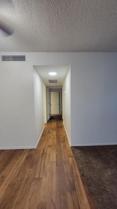 Inviting hallway with elegant wood flooring leading to multiple rooms, creating a warm and welcoming entrance.