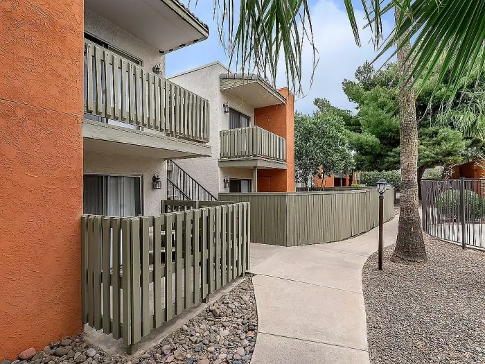 Beautiful apartment courtyard with lush green lawn, mature trees, picnic area, and charming pathway.