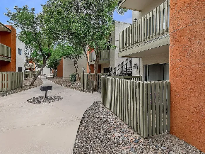 Beautiful apartment courtyard with lush green lawn, mature trees, picnic area, and charming pathway.