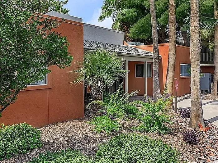 Beautiful apartment courtyard with lush green lawn, mature trees, picnic area, and charming pathway.