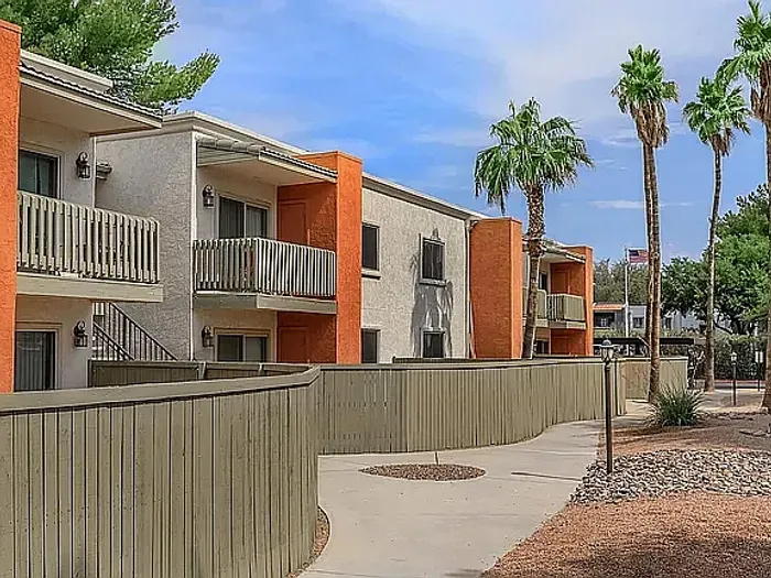 Beautiful apartment courtyard with lush green lawn, mature trees, picnic area, and charming pathway.