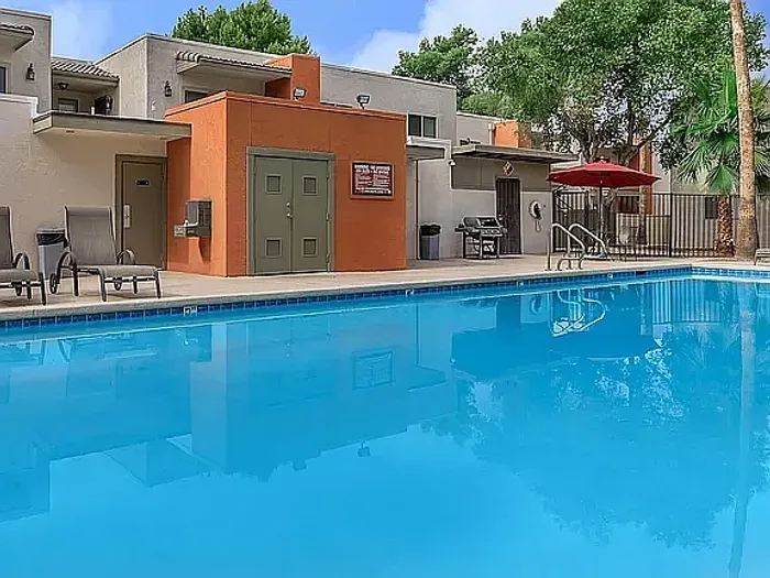 Beautiful apartment courtyard with lush green lawn, mature trees, picnic area, and charming pathway.